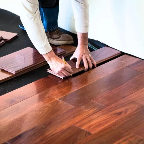 Installer fitting a hardwood board into place
